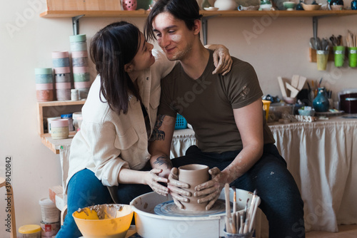 Loving couple dating in pottery workshop  man and woman sit at the pottery wheel and modeling clay