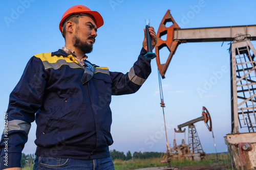 Oil refining. A man takes a sample of oil at an oil field