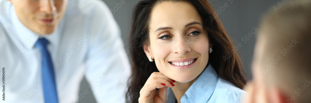 Young business woman in blue shirt communicates with two men in office portrait. Negotiations with customer and conclusion of transactions concept. Young business woman in blue shirt communicates with two men in office portrait. Negotiations with customer and conclusion of transactions concept.
