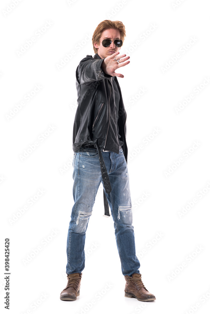 Rebellious displeased young biker or rocker style man showing stop hand sign to camera. Full body length isolated on white background. Rebellious displeased young biker or rocker style man showing stop hand sign to camera. Full body length isolated on white background.