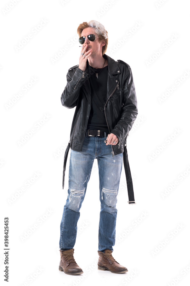 Cool macho confident biker style young man with sunglasses smoking cigarette exhale smoke. Full body length isolated on white background. Cool macho confident biker style young man with sunglasses smoking cigarette exhale smoke. Full body length isolated on white background.