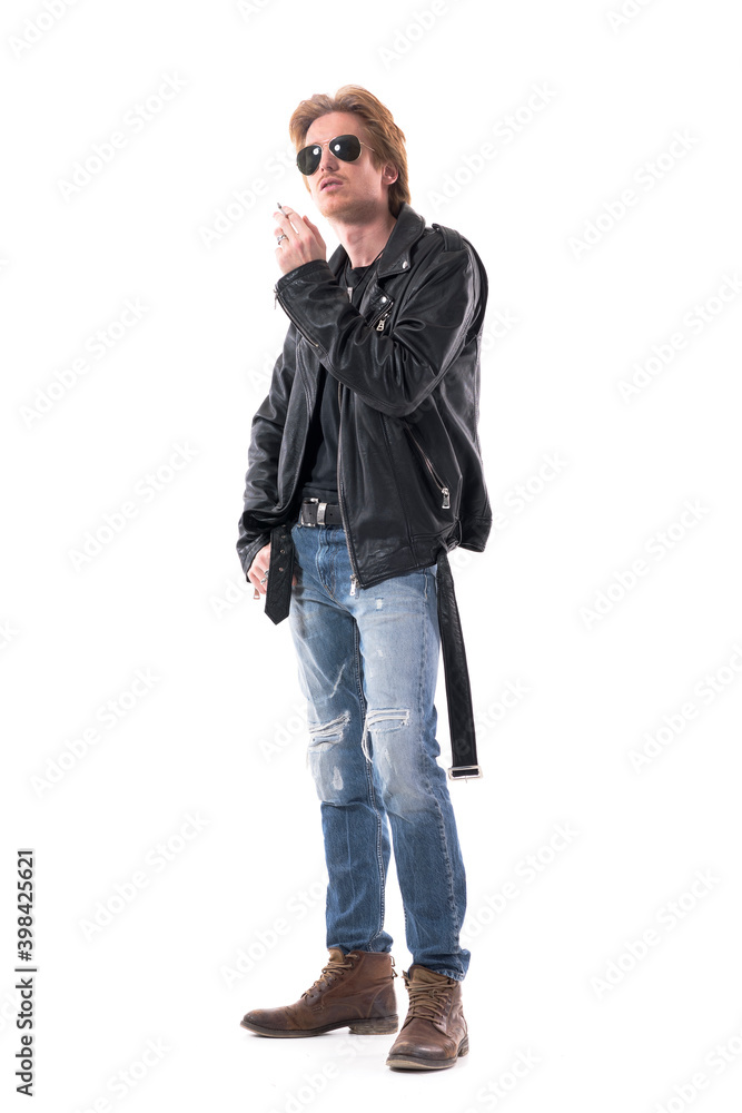 Stylish macho biker man in leather jacket and sunglasses smoking cigarette looking up. Full body length isolated on white background. Stylish macho biker man in leather jacket and sunglasses smoking cigarette looking up. Full body length isolated on white background.
