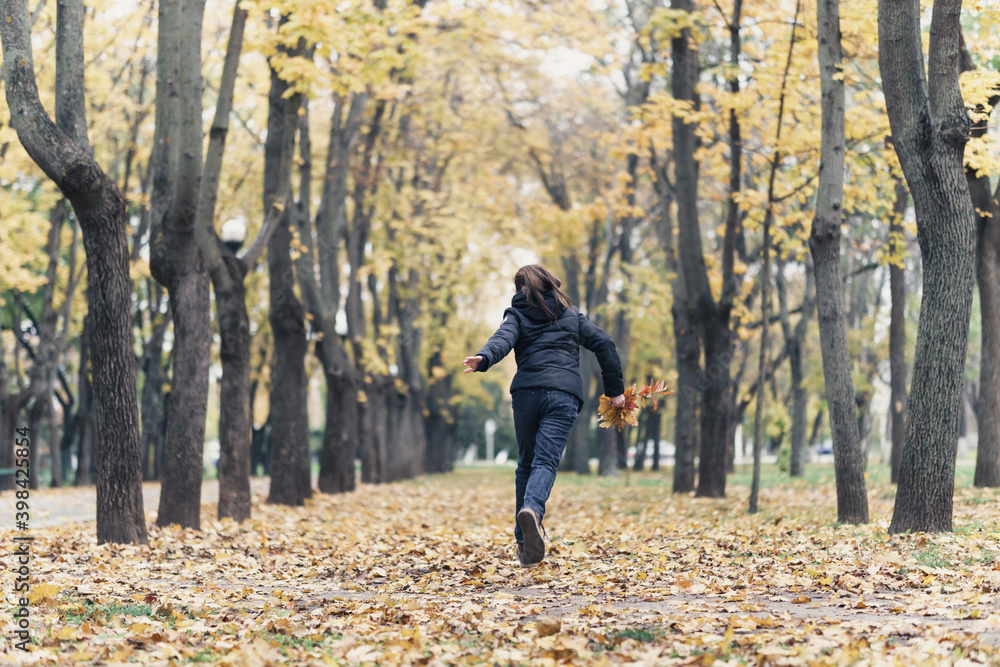 a girl running through the park and enjoys autumn, beautiful nature with yellow leaves a girl running through the park and enjoys autumn, beautiful nature with yellow leaves