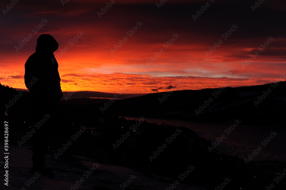 Obraz premium Black silhouette on mountain plateau during sunset with colorful red, violet, orange sky and clouds in winter in Scandinavia