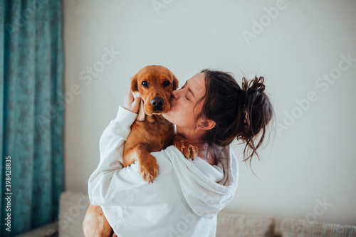 A girl in a white hoodie kisses a dog