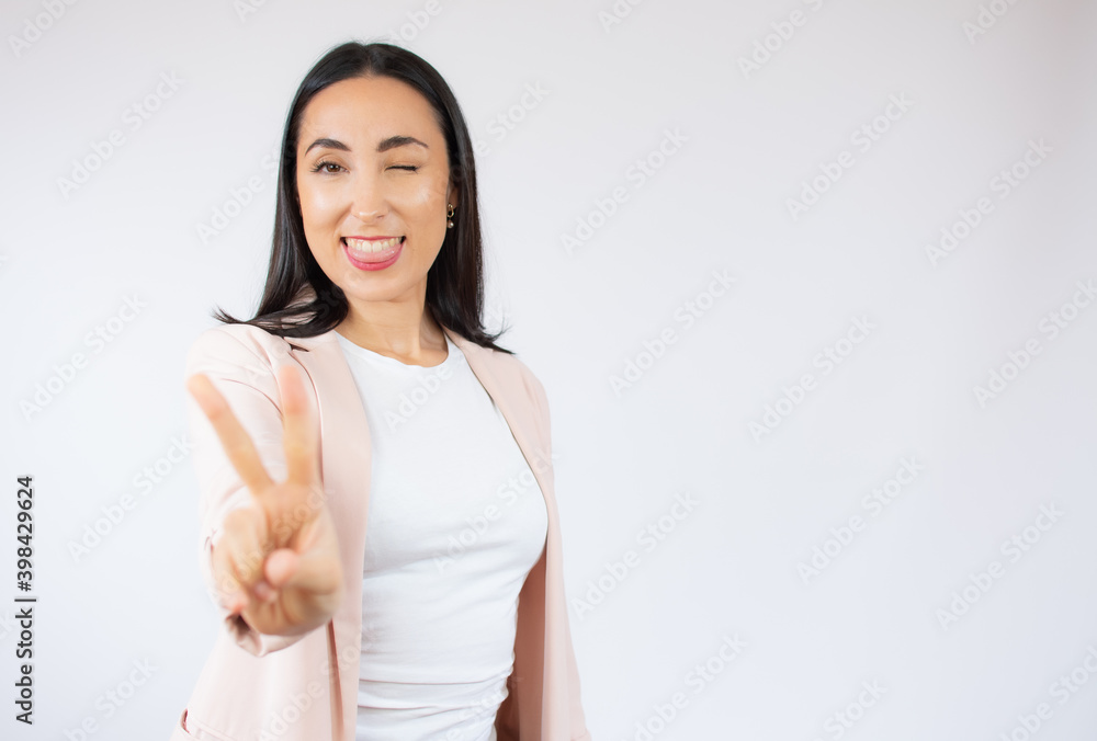 Portrait of gorgeous brunette business woman looking at camera with smile and showing peace sign with fingers isolated over white background Portrait of gorgeous brunette business woman looking at camera with smile and showing peace sign with fingers isolated over white background