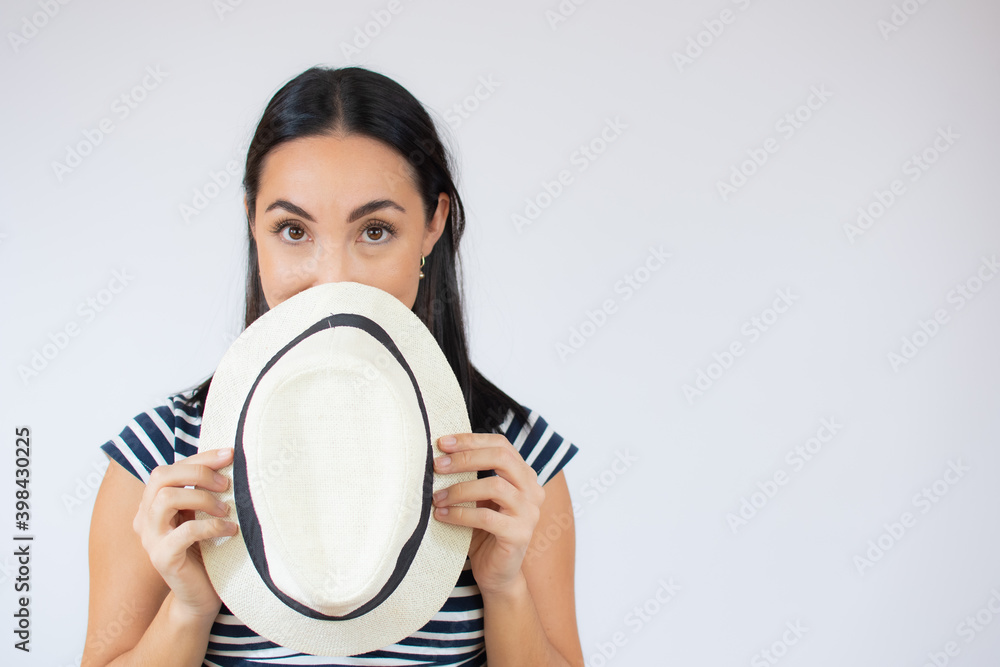 Young beautiful woman covering her mouth with a straw hat over white background. Young beautiful woman covering her mouth with a straw hat over white background.