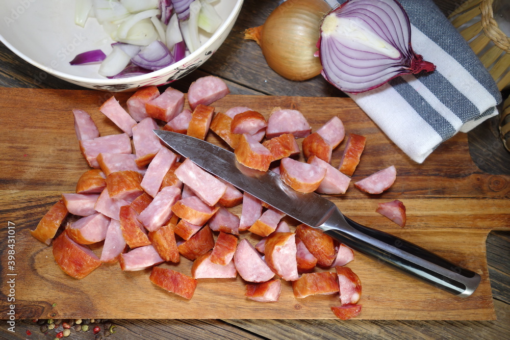 Sausage cut on a wooden board and onion . Preparation of the dish - letcho Sausage cut on a wooden board and onion . Preparation of the dish - letcho