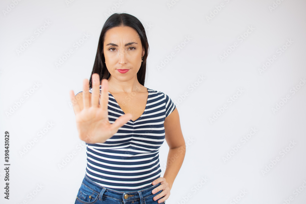 Portrait of a serious young woman standing with outstretched hand showing stop gesture isolated over white background Portrait of a serious young woman standing with outstretched hand showing stop gesture isolated over white background