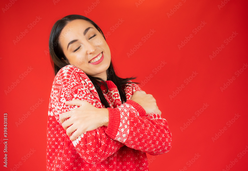 Portrait of a pretty young woman in red sweater hugging herself. Concept of selfish emotion. Portrait of a pretty young woman in red sweater hugging herself. Concept of selfish emotion.