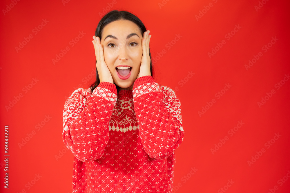 Young woman in winter sweater surprised over red background. Young woman in winter sweater surprised over red background.