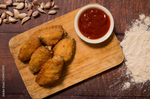Fried chicken wings and tometo sauce on a wooden floor with a ingredient.