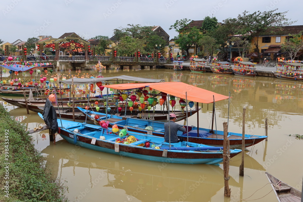 Hoi An, Vietnam, December 10, 2020: Boats adorned with multi-colored lanterns on the bank of the Thu Bon River in Hoi An