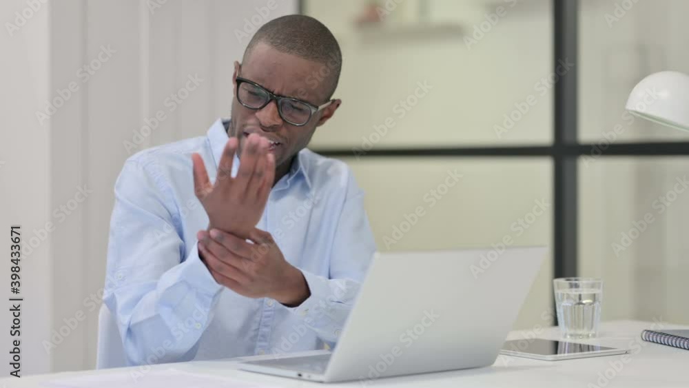 African Man having Wrist Pain while Typing on Laptop African Man having Wrist Pain while Typing on Laptop