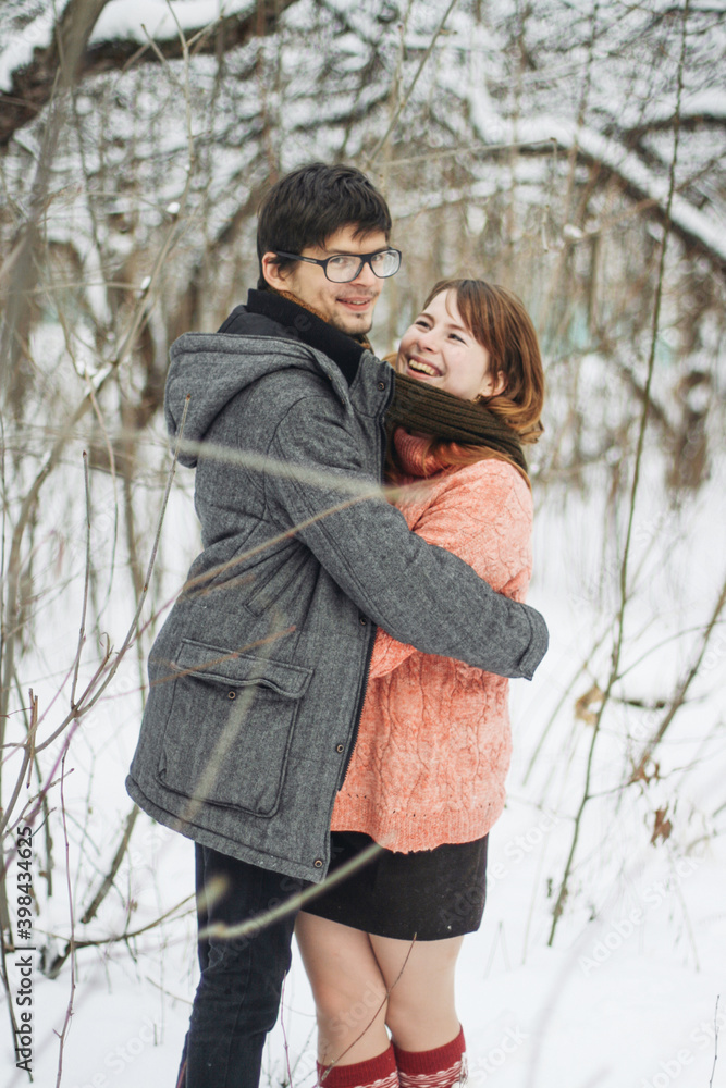 A couple in winter clothes hugging in a winter forest A couple in winter clothes hugging in a winter forest