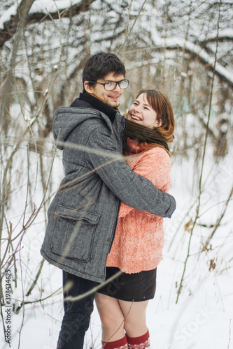 A couple in winter clothes hugging in a winter forest
