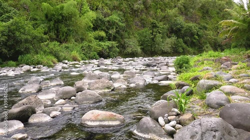 Rivière naturelle de Bras Canot à l'île de La Réunion montrant des galets de pierre et de l'eau douce des montagnes. La végétation autour de la rivière est tropicale et l'eau de la rivière est claire