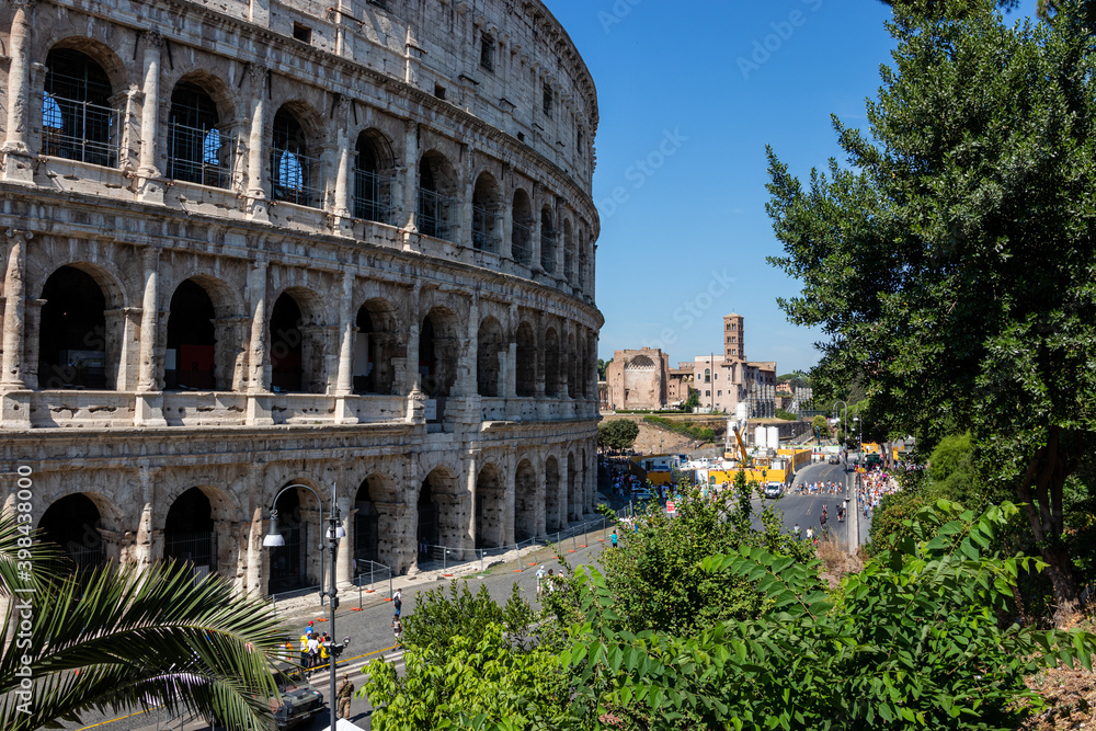 Roman colosseum among green trees. An ancient arched structure.
