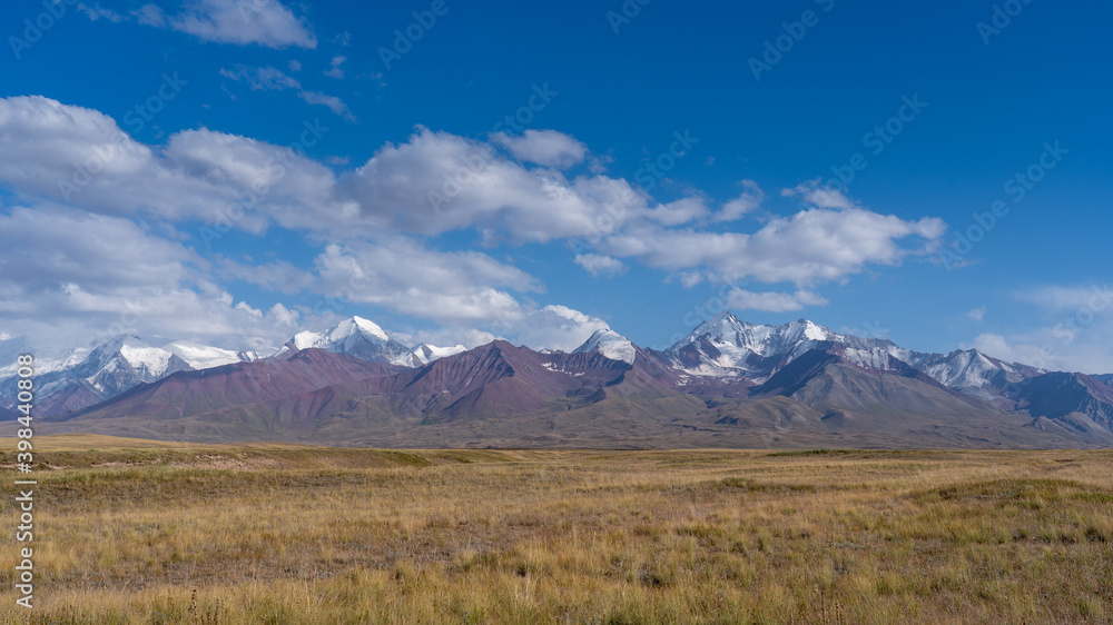 Panorama of snow-capped Trans-Alay mountain range in Sary Tash valley, Kyrgyzstan with pasture foreground along the Pamir Highway near border with Tajikistan