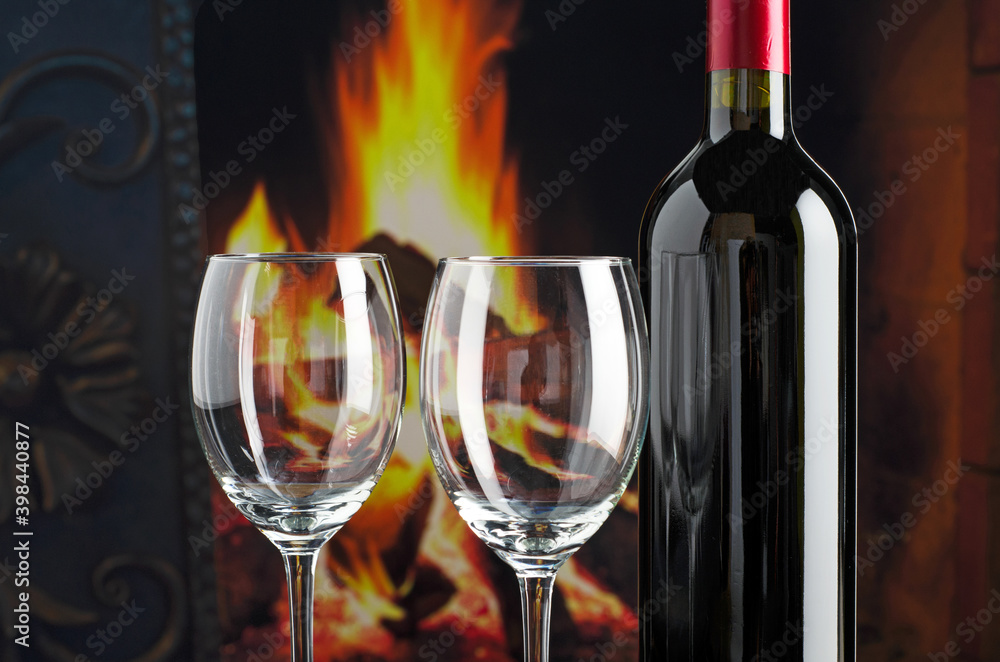 Wine bottle and wineglass on the background of the fire fireplace