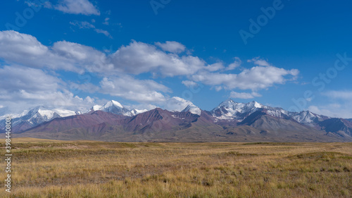 Panorama of snow-capped Trans-Alay mountain range in Sary Tash valley, Kyrgyzstan with pasture foreground along the Pamir Highway near border with Tajikistan
