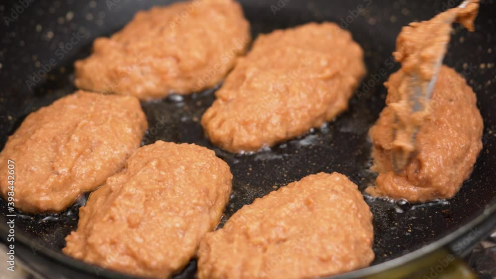 Close up fried juicy fish cutlets in frying pan. Hand flips Close up fried juicy fish cutlets in frying pan. Hand flips