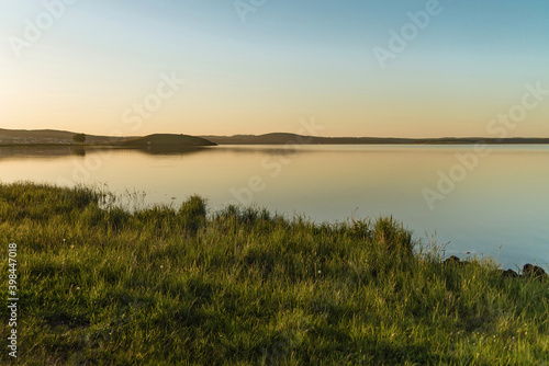 beautiful lake landscape at sunset. green grass, water and clear sky at sunset