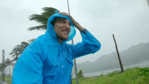 A man in a raincoat is under a hevy rain and stormy wind. Shot on an action camera. Tropical storm concept. Contains natural sound photo