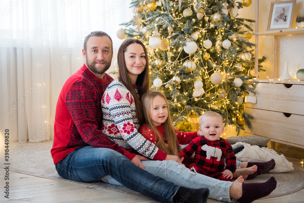 happy family includ four  people sit on the carpet under chrismas tree