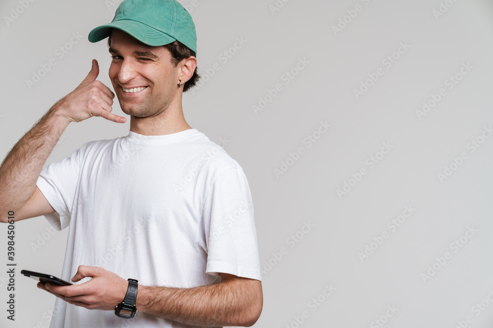 Handsome happy guy showing handset gesture while using mobile phone Handsome happy guy showing handset gesture while using mobile phone