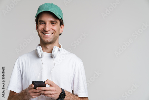 Handsome smiling guy with headphones using mobile phone