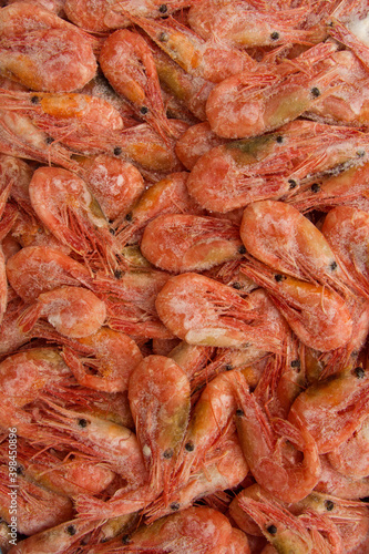 Close-up of a stack of frozen pink shrimp. Frozen shrimp background. veritable format, texture.