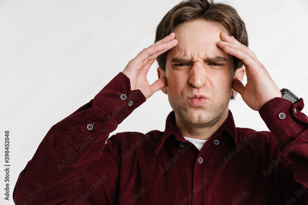 Handsome unhappy young man with headache rubbing his forehead Handsome unhappy young man with headache rubbing his forehead