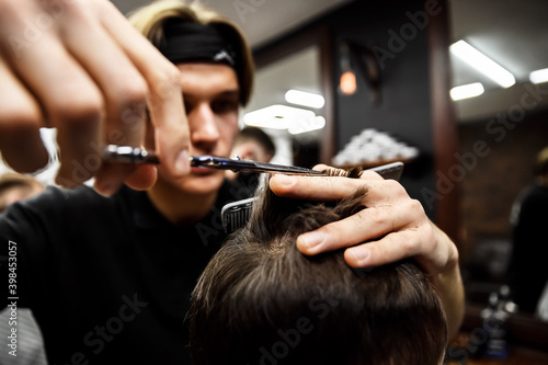 the process of men's haircuts in a stylish barbershop. men's hairdresser, beauty salon. close-up of the hands of a master who cuts a man with scissors. hairdressing accessories. stylish hairstyle