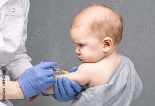 Doctor injecting a vaccine in arm of baby girl photo