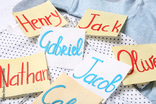 Many sticky notes with different baby names on child's clothes, closeup