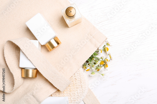 Flat lay composition with chamomile flowers and cosmetic products on white table