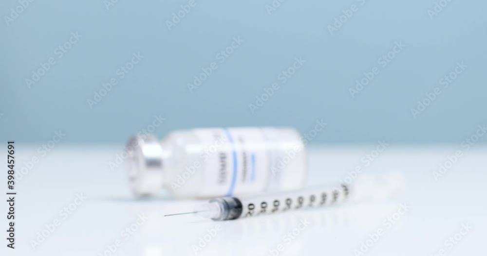 Research and development of new cure for diseases. Close-up of female doctor hands in blue medical gloves with transparent liquid coronavirus vaccine bottle and syringe for injection in the laboratory Research and development of new cure for diseases. Close-up of female doctor hands in blue medical gloves with transparent liquid coronavirus vaccine bottle and syringe for injection in the laboratory