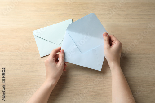 Woman with white paper envelopes at wooden table, top view