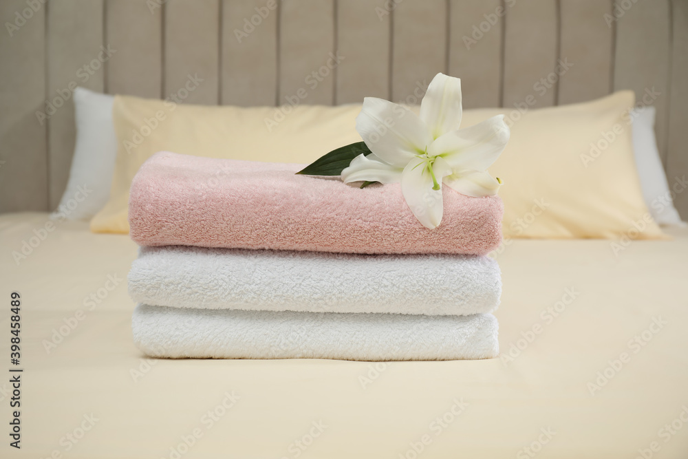 Stack of clean towels and flower on bed Stack of clean towels and flower on bed