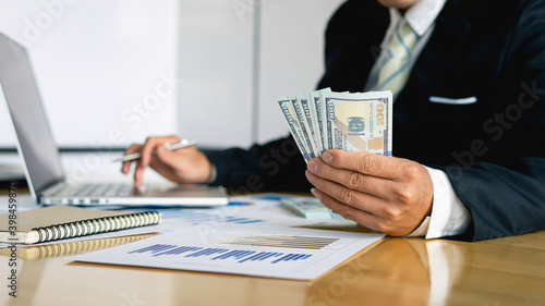Businessman accountant counting money and making notes at report doing finances and calculate the cost of investment and analyzing financial data, Financing Accounting Banking Concept.