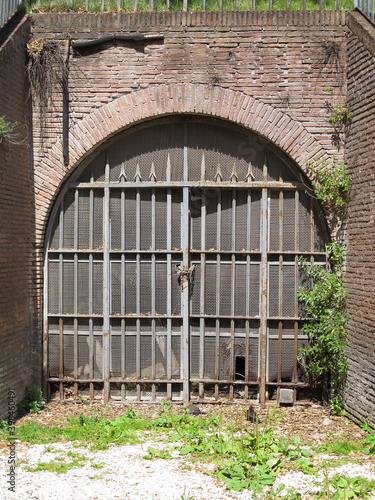 A gate in an old closed-up castle, which is made of brick, in the sun. Image has copy space.