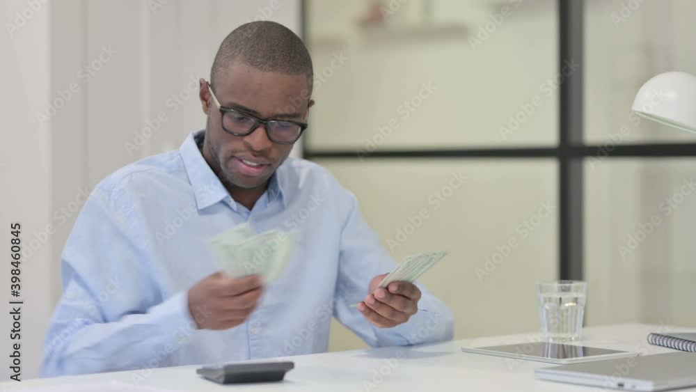 African Man using Calculator while Counting Dollars African Man using Calculator while Counting Dollars