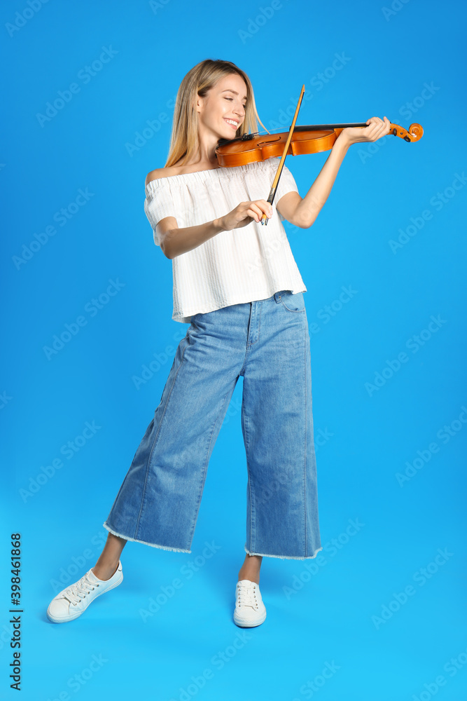 Beautiful woman playing violin on blue background Beautiful woman playing violin on blue background