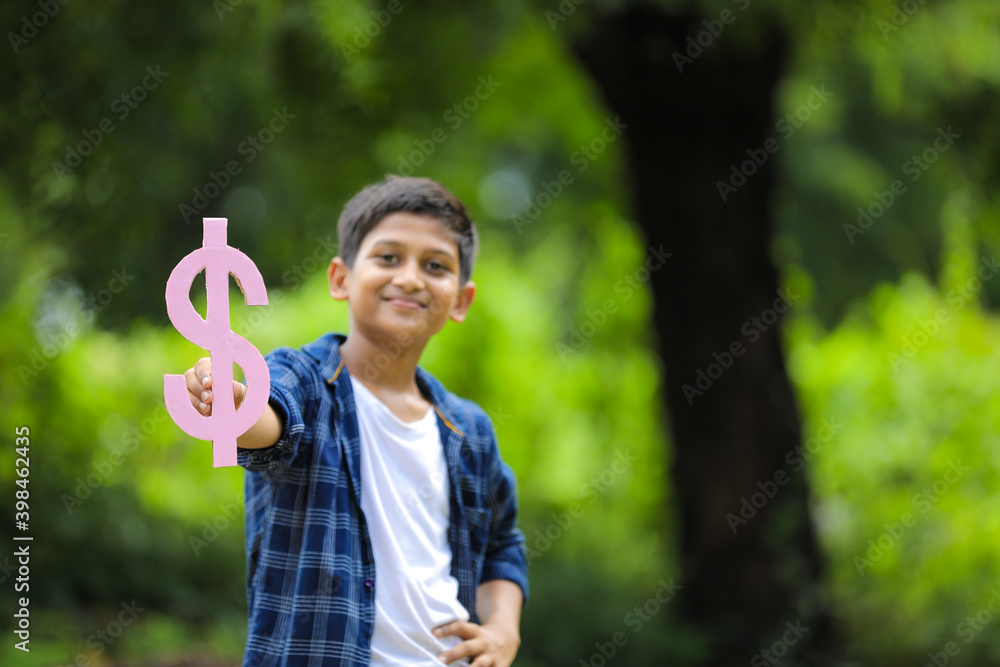 Cute indian little child holding dollar Sign on nature Background Cute indian little child holding dollar Sign on nature Background