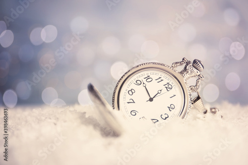Pocket watch on snow against blurred lights, space for text. New Year countdown