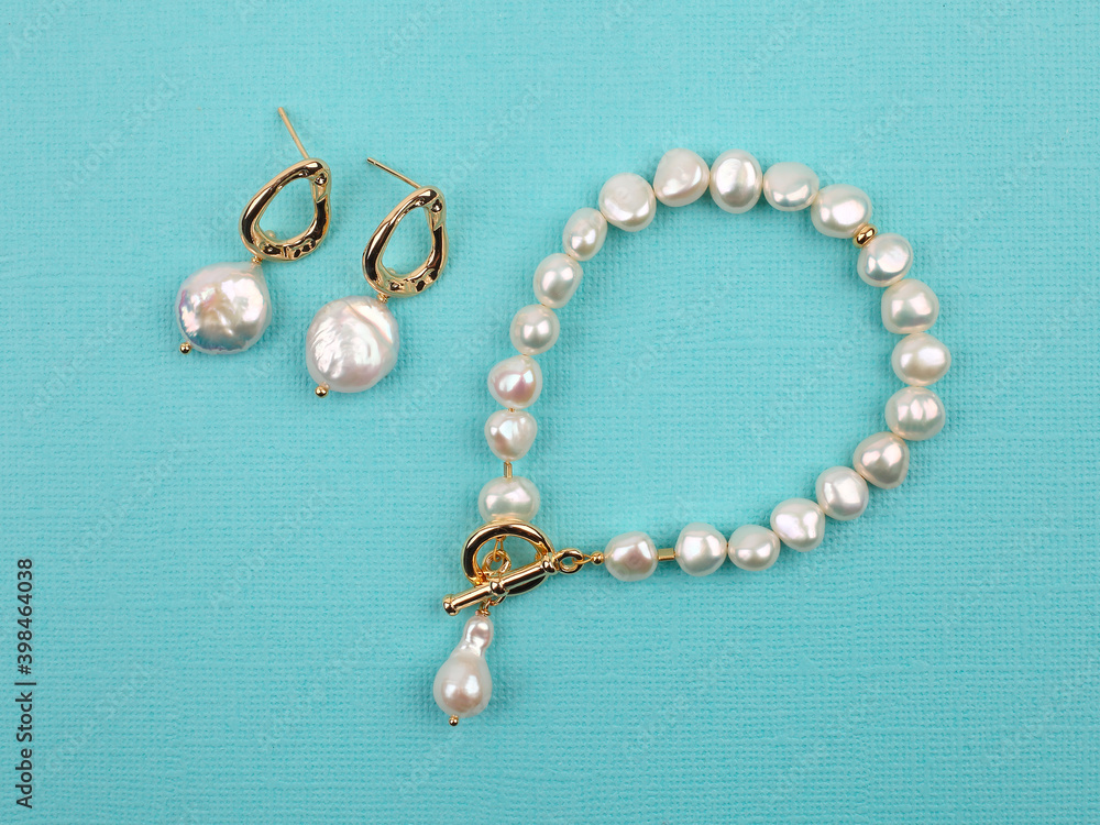 Luxury elegant baroque pearl earrings and bracelet on bright turquoise textured background Luxury elegant baroque pearl earrings and bracelet on bright turquoise textured background