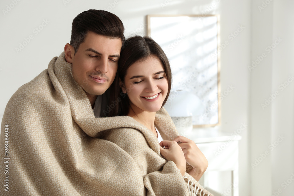 Obraz premium Happy couple covered with warm beige plaid indoors