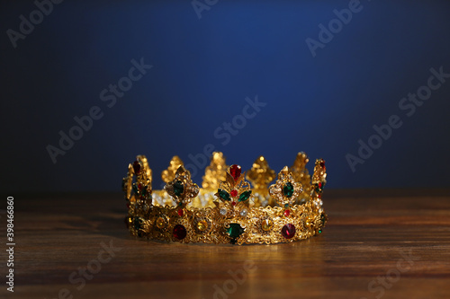 Beautiful golden crown with gems on wooden table. Fantasy item