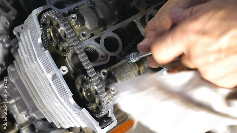 Top view on disassembled motorcycle engine. Professional mechanic repairing motor using tool. Repairer working in garage or workshop. Man engaged servicing cars or motorbikes. Slow motion Close up Top view on disassembled motorcycle engine. Professional mechanic repairing motor using tool. Repairer working in garage or workshop. Man engaged servicing cars or motorbikes. Slow motion Close up